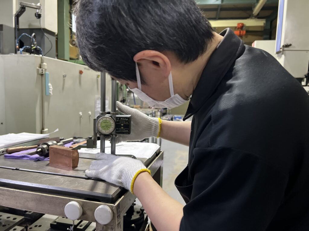 ハイトゲージで銅電極を測定する技術者